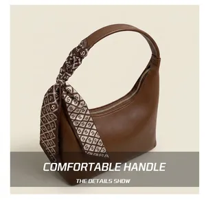 Detail of brown leather handbag featuring a silk scarf wrapped handle and smooth zipper