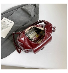 Interior detail of a dark red shoulder bag with white stitching and large capacity