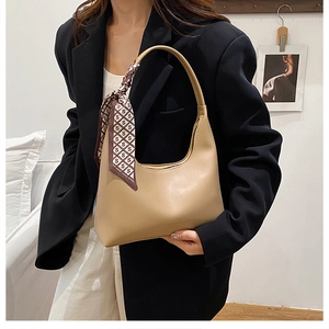 Détail du sac demi-lune kaki avec un foulard en soie élégant noué sur la poignée