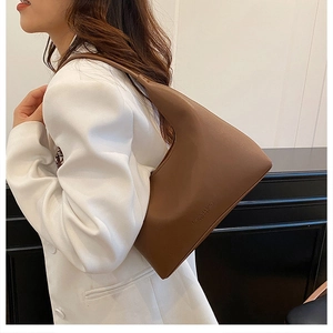 Detailed view of the dark brown leather hobo bag worn with a white professional suit