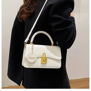 Dettaglio borsa a mano bianca con serratura in metallo dorato e ciondolo Fashion