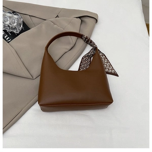 Détail du sac hobo marron foncé avec foulard imprimé élégant noué sur la poignée