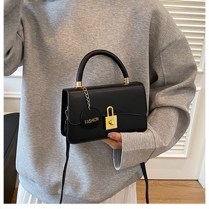 Dettaglio della borsa in pelle nera opaca con chiusura dorata e ciondolo moda