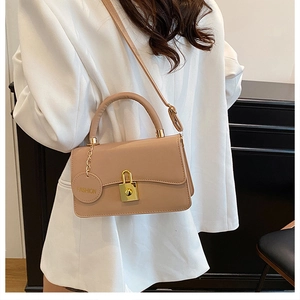 Dettaglio borsa a tracolla in pelle beige con chiusura dorata e targhetta fashion