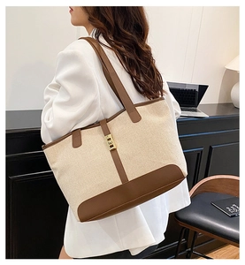 Model wearing a canvas tote bag with brown leather trim in an office setting