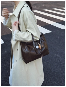 Street style view of large dark brown leather tote bag worn with a beige trench coat
