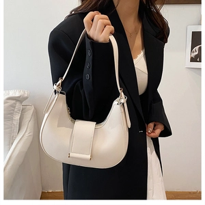 Chic white crescent shoulder bag in matte leather worn by a model in black suit