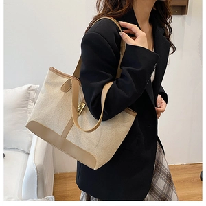 Detailed shot of canvas and leather tote with gold metal twist lock worn by a model