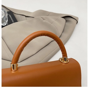 Dettaglio del manico della borsa marrone con hardware dorato e similpelle di alta qualità