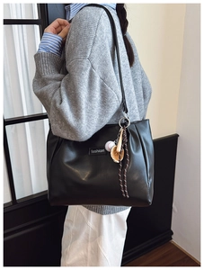 Close-up of black PU leather tote bag featuring a creative baseball-themed charm and label