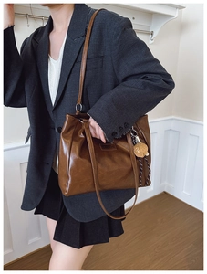 Détail d'un sac cabas marron foncé avec breloque dé et plaque de mode en similicuir texturé