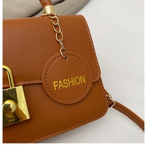 Dettaglio della borsa in pelle marrone con chiusura dorata ed etichetta moda