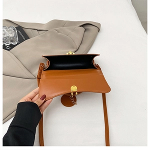 Vista dall'alto di una borsa a tracolla marrone aperta con interno nero e chiusura dorata