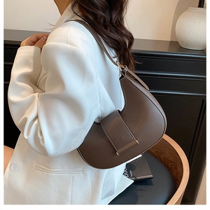 Dark brown crescent shoulder bag styled with a white blazer for a minimalist look