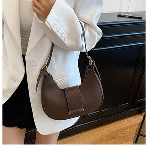 Detail of a dark brown half-moon underarm bag made of glossy PU leather with gold hardware