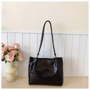 Sac fourre-tout minimaliste en cuir synthétique noir avec fines anses dans un décor chic