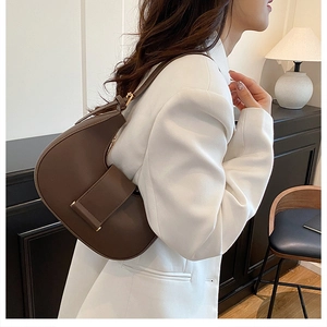 Detail of a dark brown crescent hobo bag with a decorative buckle and gold hardware