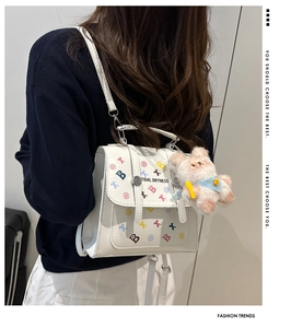 Détail du sac à dos blanc avec motifs lettrés et un pendentif ours en peluche rose mignon