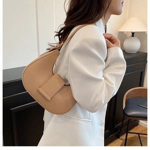 Side view of a beige crescent hobo bag with wide decorative strap worn on the shoulder