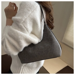 Macro side view of a grey leopard print hobo bag worn by a model in a cozy white sweater