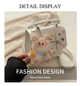 Détail du sac bandoulière en cuir blanc avec ours en peluche rose et fermoir argenté