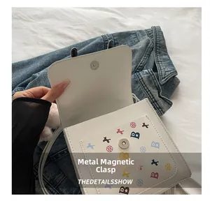 Détail de la boucle magnétique en métal sur le petit sac carré en cuir blanc