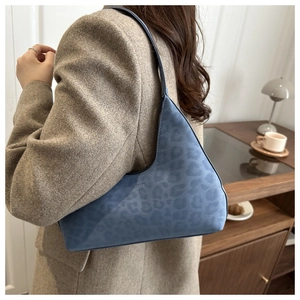 Detail of blue leopard print suede bag with thin shoulder strap on model's side