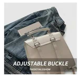 Gros plan de la boucle argentée et du cuir verni blanc sur un petit sac à bandoulière
