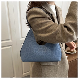 Close-up of blue leopard print shoulder bag in suede texture styled with a brown coat