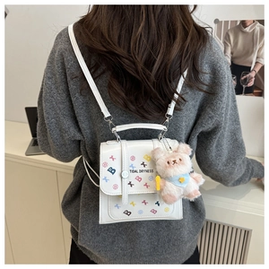 Détail d'un sac à dos blanc en PU avec motifs colorés et breloque ours en peluche mignonne