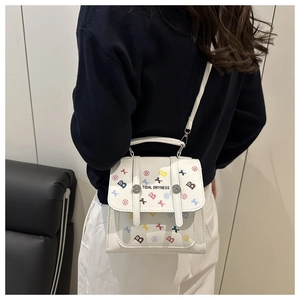 Gros plan du mini sac à dos blanc à motif étoile et rabat porté par un mannequin
