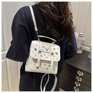 Détail d'un mini sac à dos blanc avec imprimés de lettres B colorées et boucles argentées