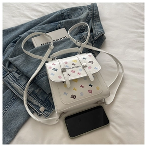 Détail du mini sac à dos blanc avec imprimés cartoon et boucles métalliques argentées