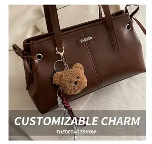 Detailed shot of brown tote bag with leather texture, fashion tag and plush bear charm