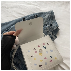Gros plan sur un sac bandoulière blanc avec logo 'B' coloré et imprimé silhouette de chien