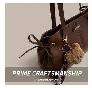 Detail of dark brown wax leather tote bag with FASHION metal plate and cute bear charm