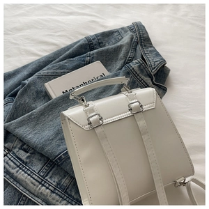Mini sac à dos en cuir blanc sur veste en jean avec livre et boucles argentées élégantes