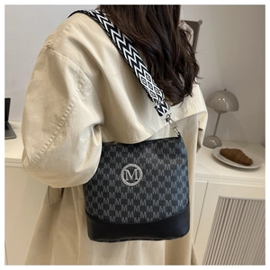 Detail of black bucket bag with M-pattern jacquard and geometric wide shoulder strap