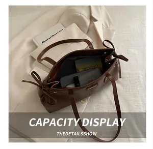 Detail view of large interior space in brown wax leather tote with ribbon and fashion label
