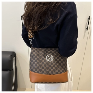 Detail showing vintage M-pattern monogram bucket bag with brown leather bottom and metal logo