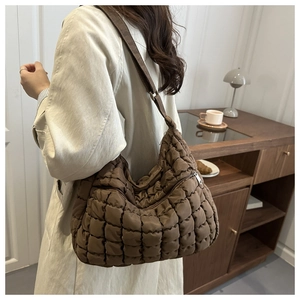 Dettaglio di una borsa shopper trapuntata marrone scuro con texture morbida e tracolla larga