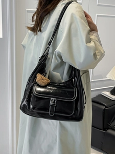 Modern black hobo shoulder bag with white contrast stitching and teddy bear charm