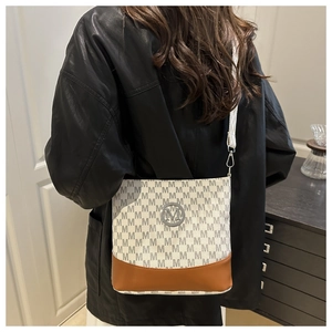 Détail de sac bandoulière avec imprimé lettre M et logo métallique rond sur la sangle