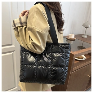 Close-up of black quilted puffer tote bag with glossy finish on a wooden table setup