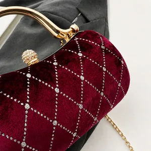 Detail of burgundy velvet clutch with quilted pattern, glitter, and rhinestone lock
