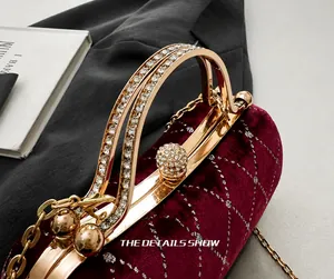Detailed close-up of velvet handbag with golden crystal handles and spherical clasp