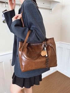 Sac fourre-tout en cuir marron avec étiquette mode et breloque biscuit en décor intérieur