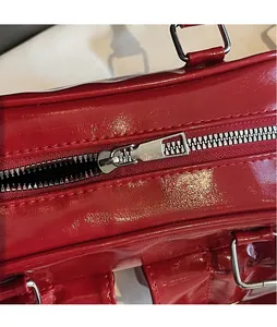 Detail of silver polished zipper and shiny red patent leather on a stylish handbag