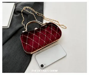 Detail of burgundy velvet evening bag with diamond lattice pattern and metallic handle