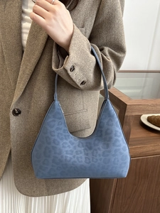 Minimalist light blue leopard embossed hobo bag shown as a shoulder bag on a model